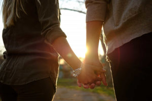 זוג מחזיקים ידיים לאור השקיעה